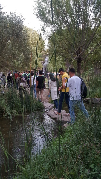 Mange deltagere går på rekke over noen steiner som utgjør en sti over en bekk